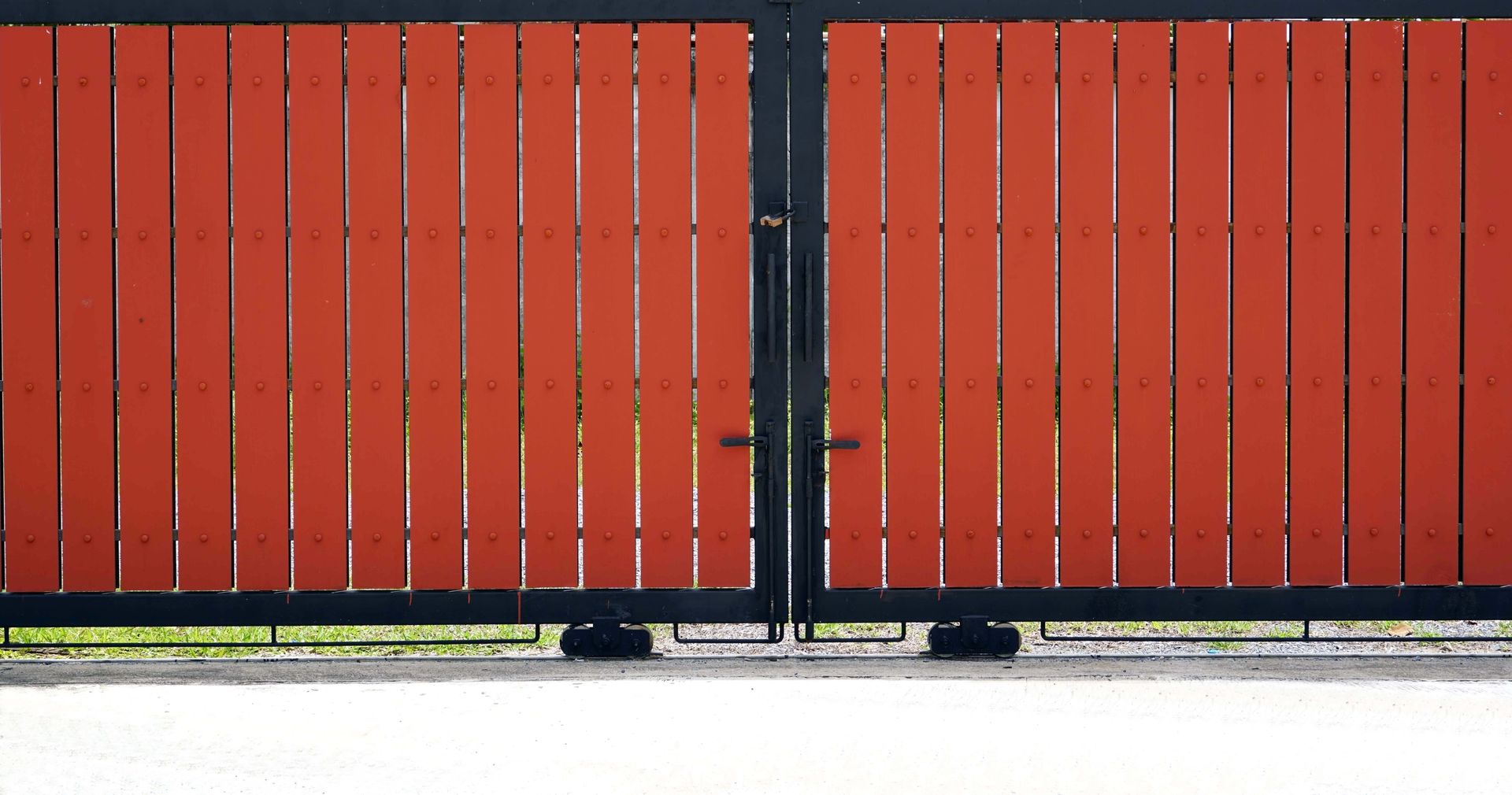 Red and black wooden gate with vertical planks, closed.
