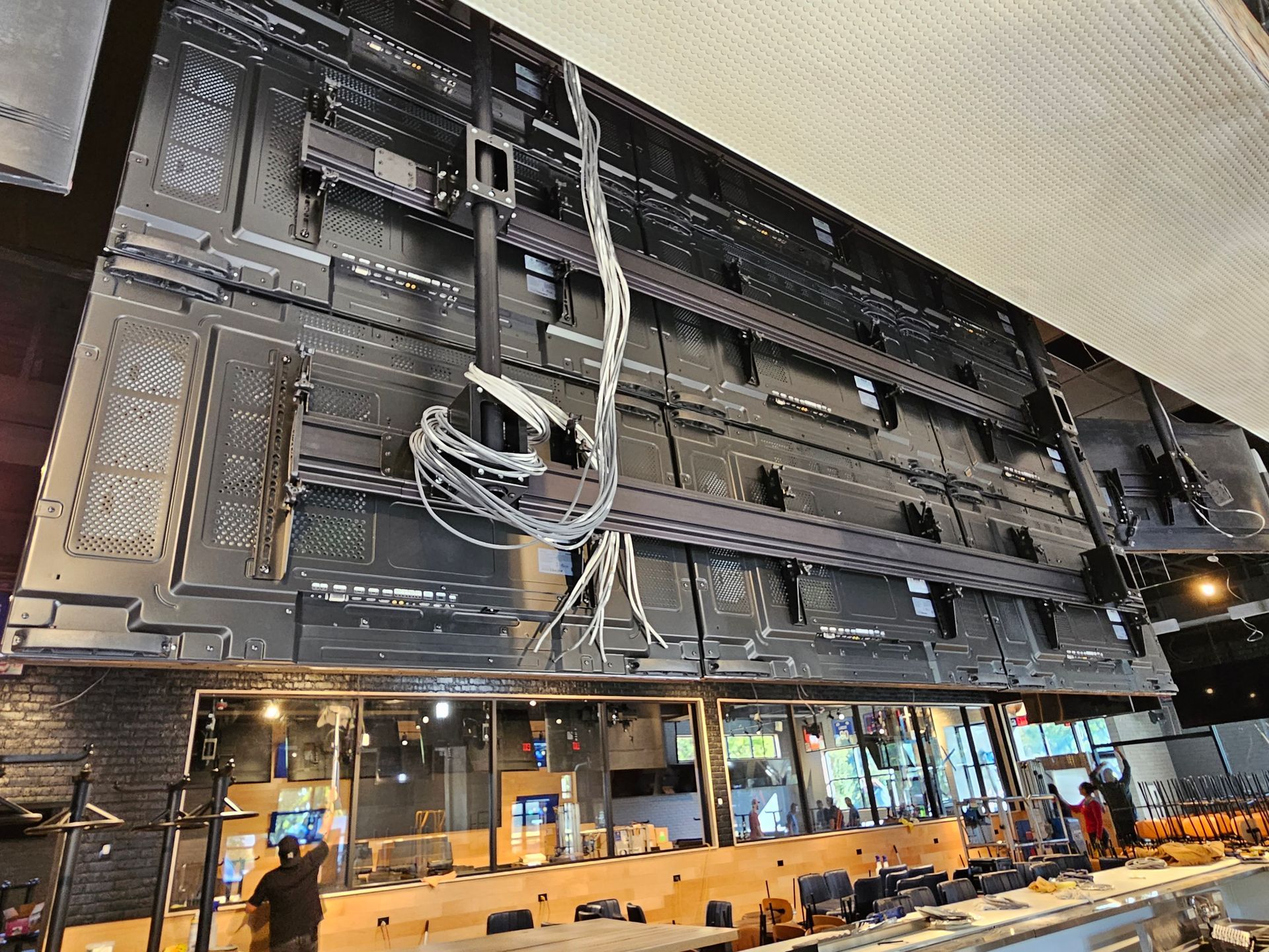 A large flat screen tv is being installed in a restaurant.