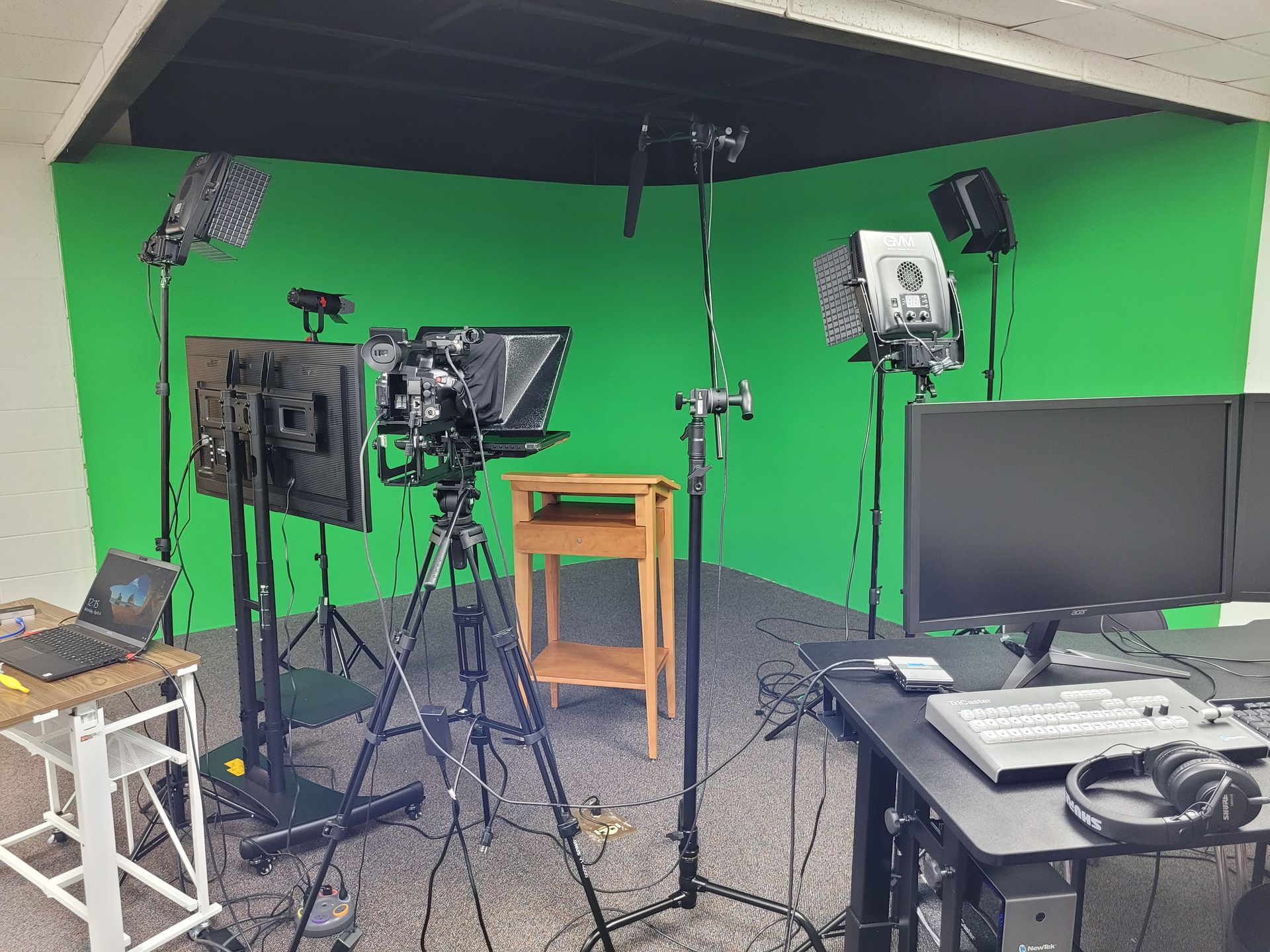 A green screen is behind a camera and monitor in a studio.