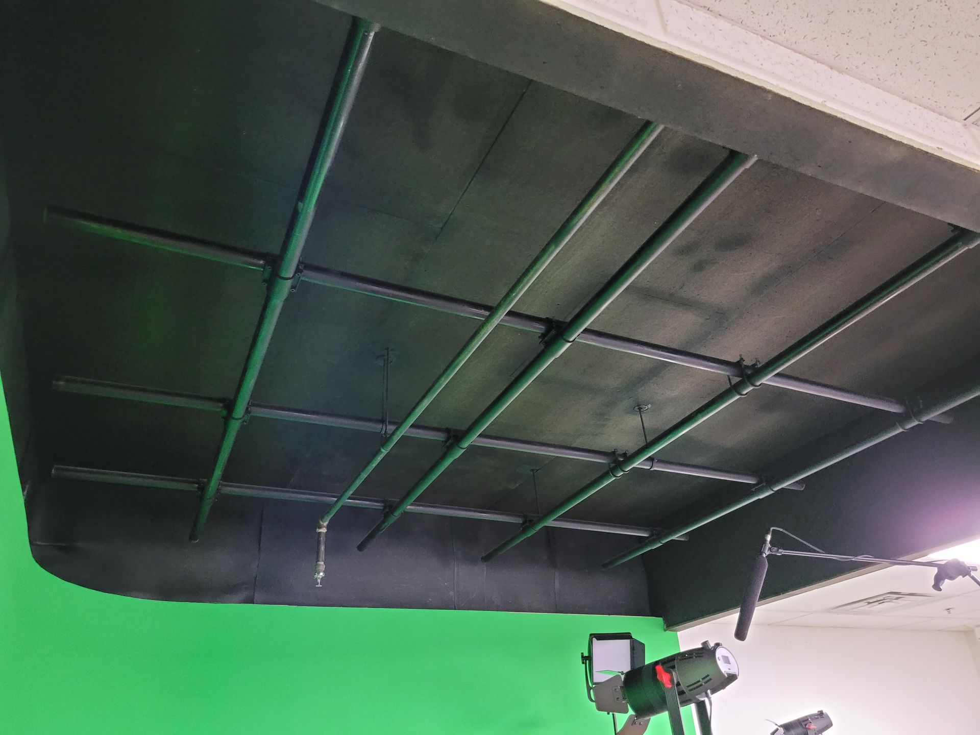 A green screen is behind a black ceiling in a room.