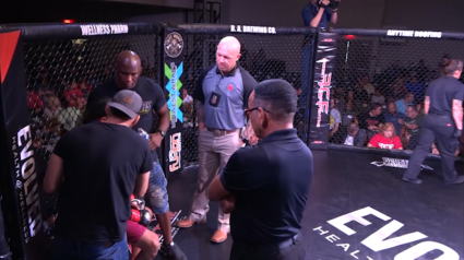 A group of men are standing around a cage with the word evo on it