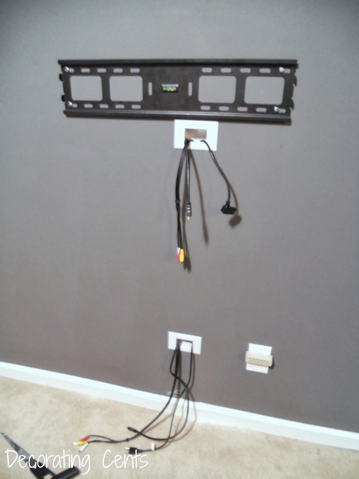 A wall with a tv mount and a bunch of wires hanging from it