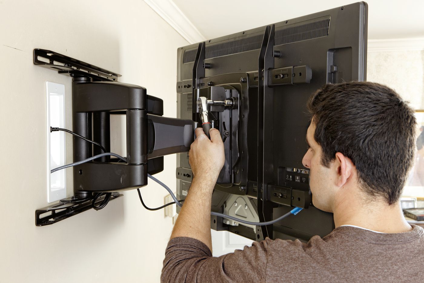 A man is mounting a flat screen tv on a wall.