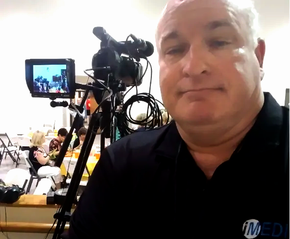 A man in a black shirt is standing in front of a video camera