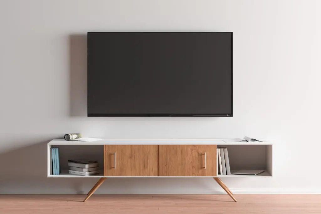 A flat screen tv is mounted on a wall above a wooden entertainment center.