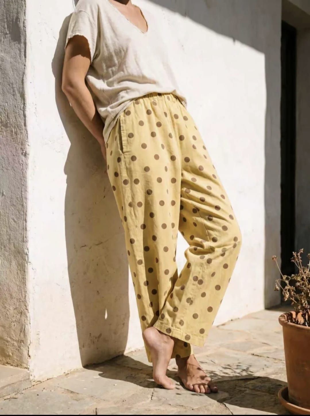 Femme en tenue blanche debout sur un balcon donnant sur la mer bleue et les arbres