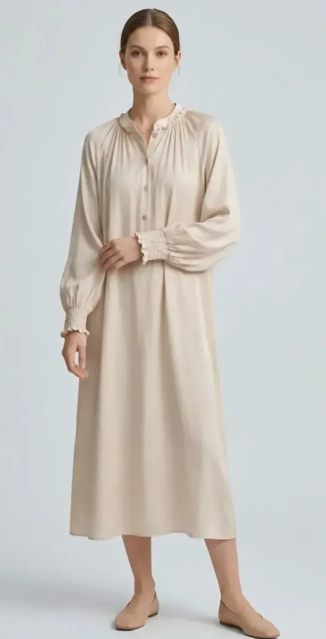 Femme en robe midi beige à manches longues, se tenant sur un fond clair.