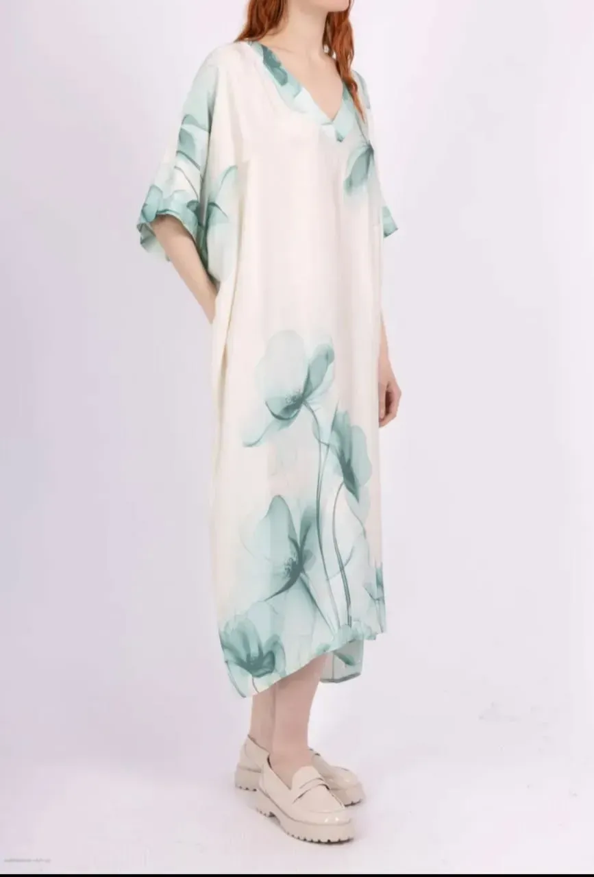 Robe midi blanche à imprimé floral turquoise et manches amples, présentée sur un mannequin devant un fond uni