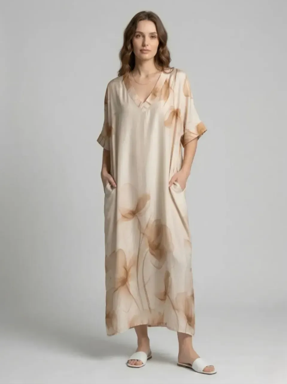 Mannequin vêtue d'une robe midi crème à imprimé abstrait et de sandales blanches, les mains dans les poches.