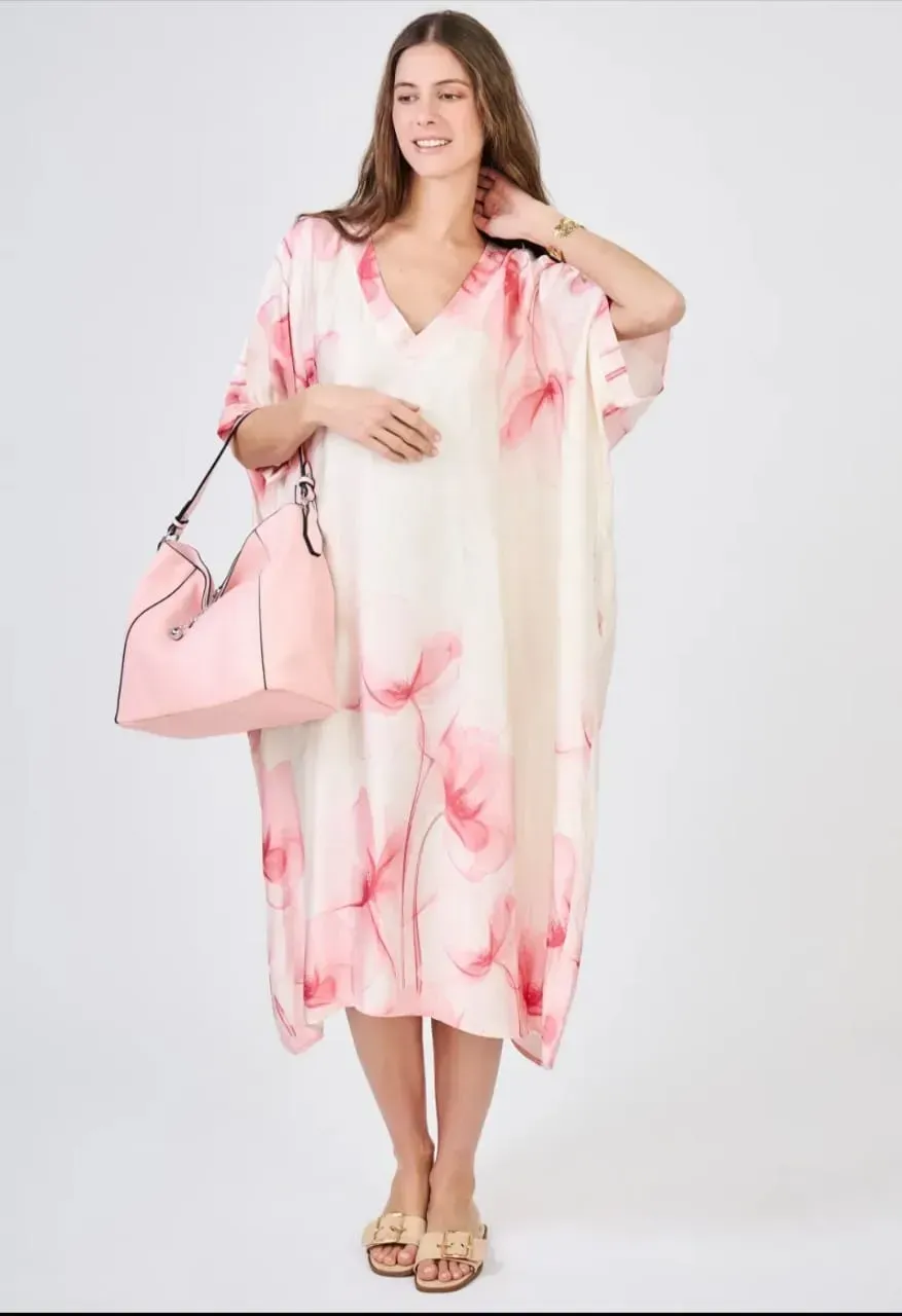 Femme portant un caftan transparent blanc et rose à motifs floraux avec un sac à main rose assorti sur fond blanc