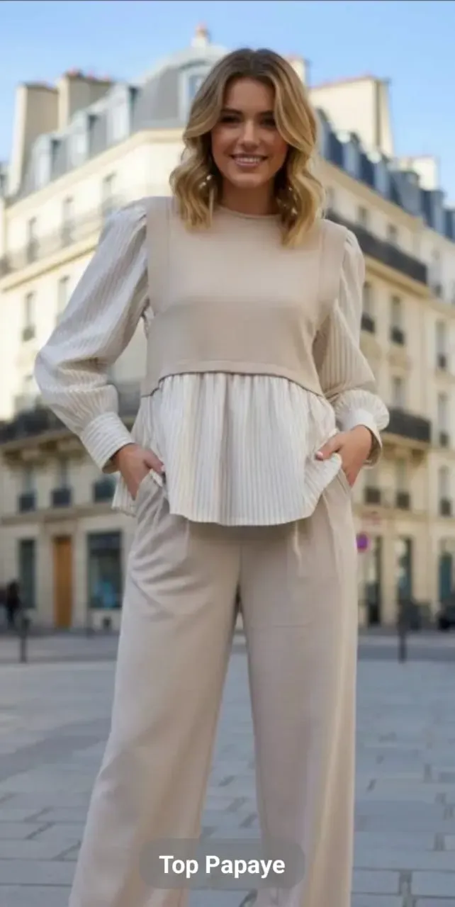 Femme vêtue de beige, debout dans une rue de la ville, les mains dans les poches, souriante