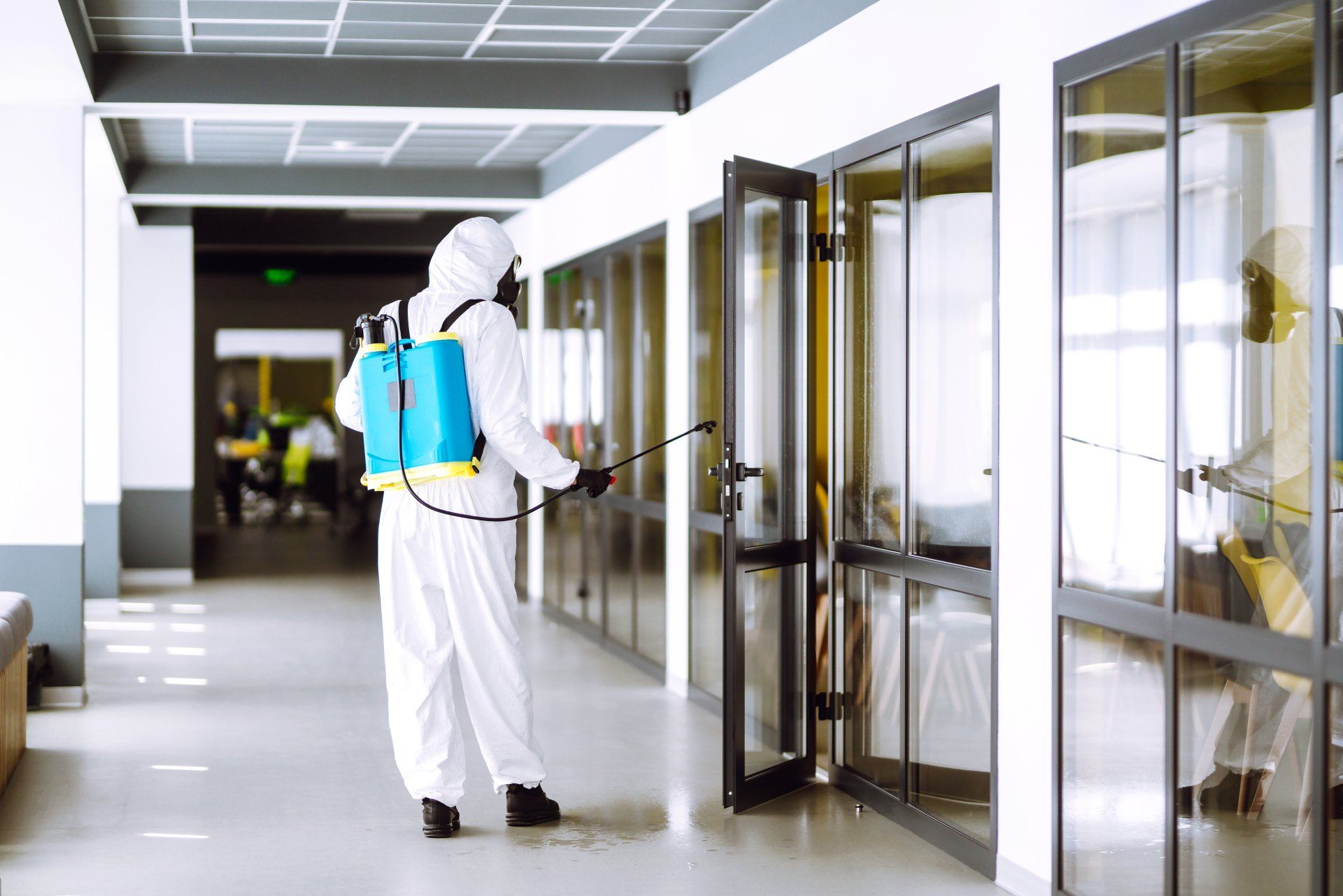 Worker Spraying Airborne Disinfectant in Building