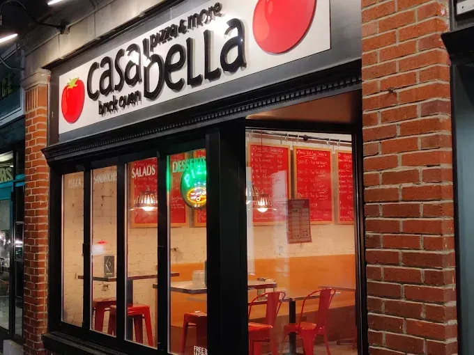 Storefront of Casa Bella Brick Oven Pizza, featuring a white sign, brick walls, and visible interior seating.