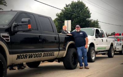 A man and a child stand between two pickup trucks labeled 