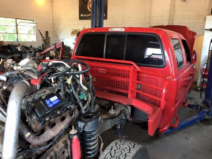 A red truck cab sits in a garage with its engine exposed for repair.
