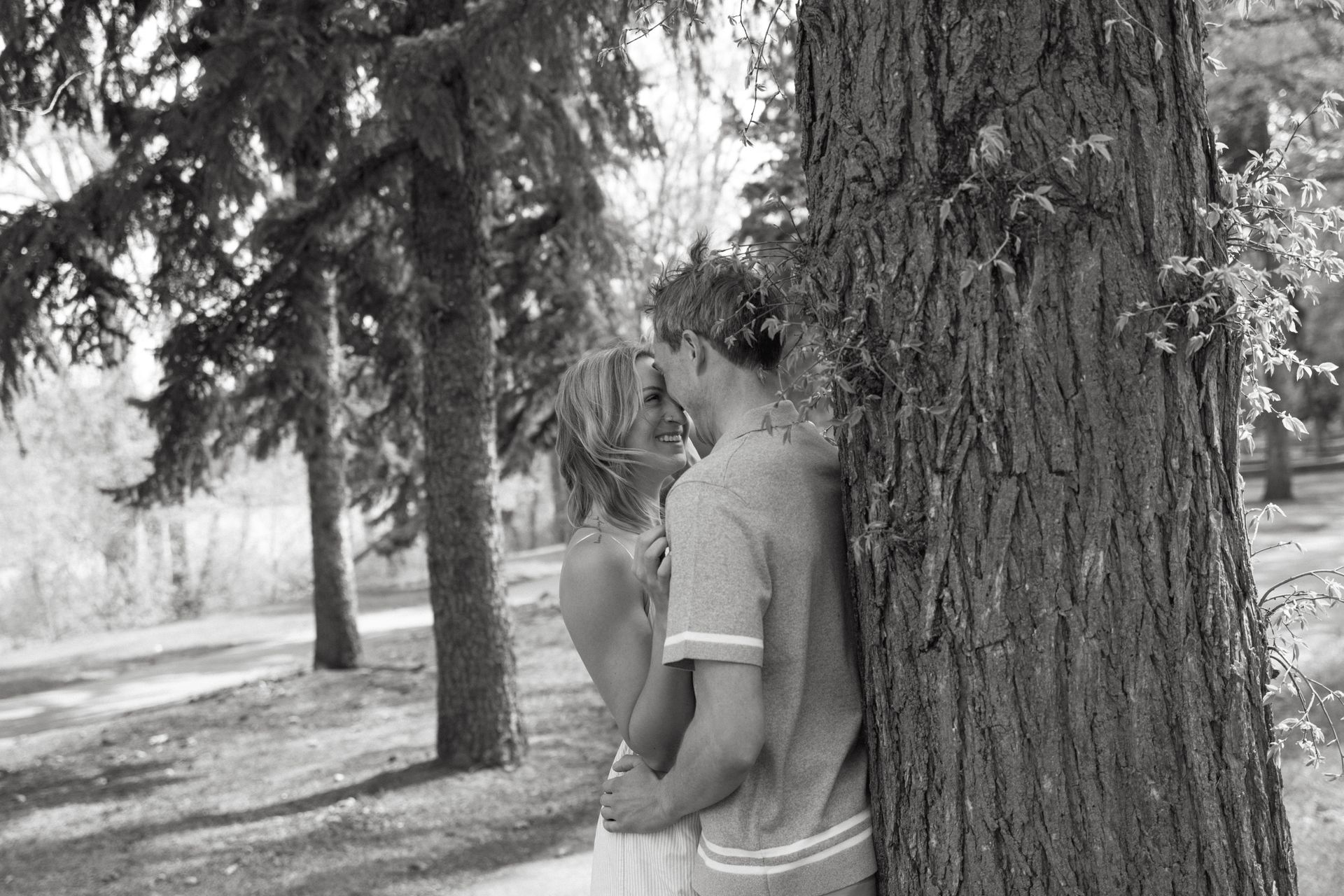Couple embracing beside a large tree in a park
