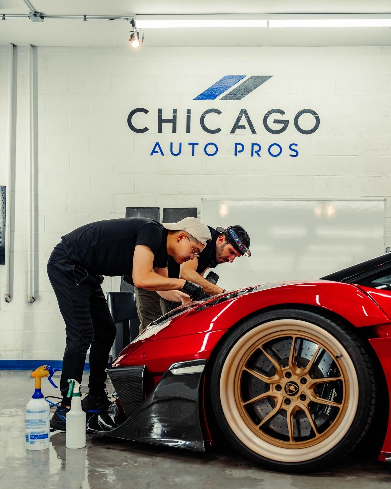 Two men are working on a red sports car at chicago auto pros