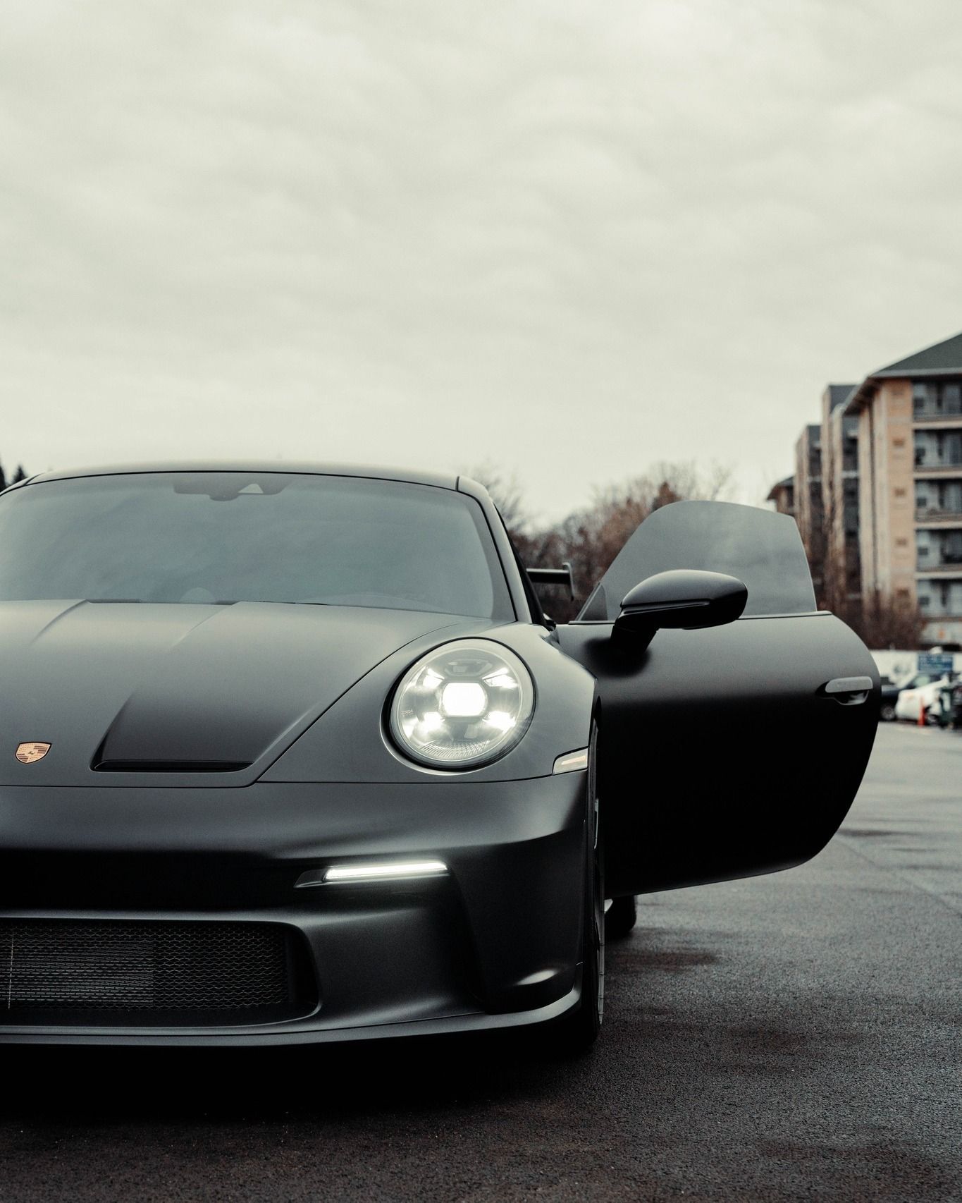 a black porsche is parked in a parking lot with its door open