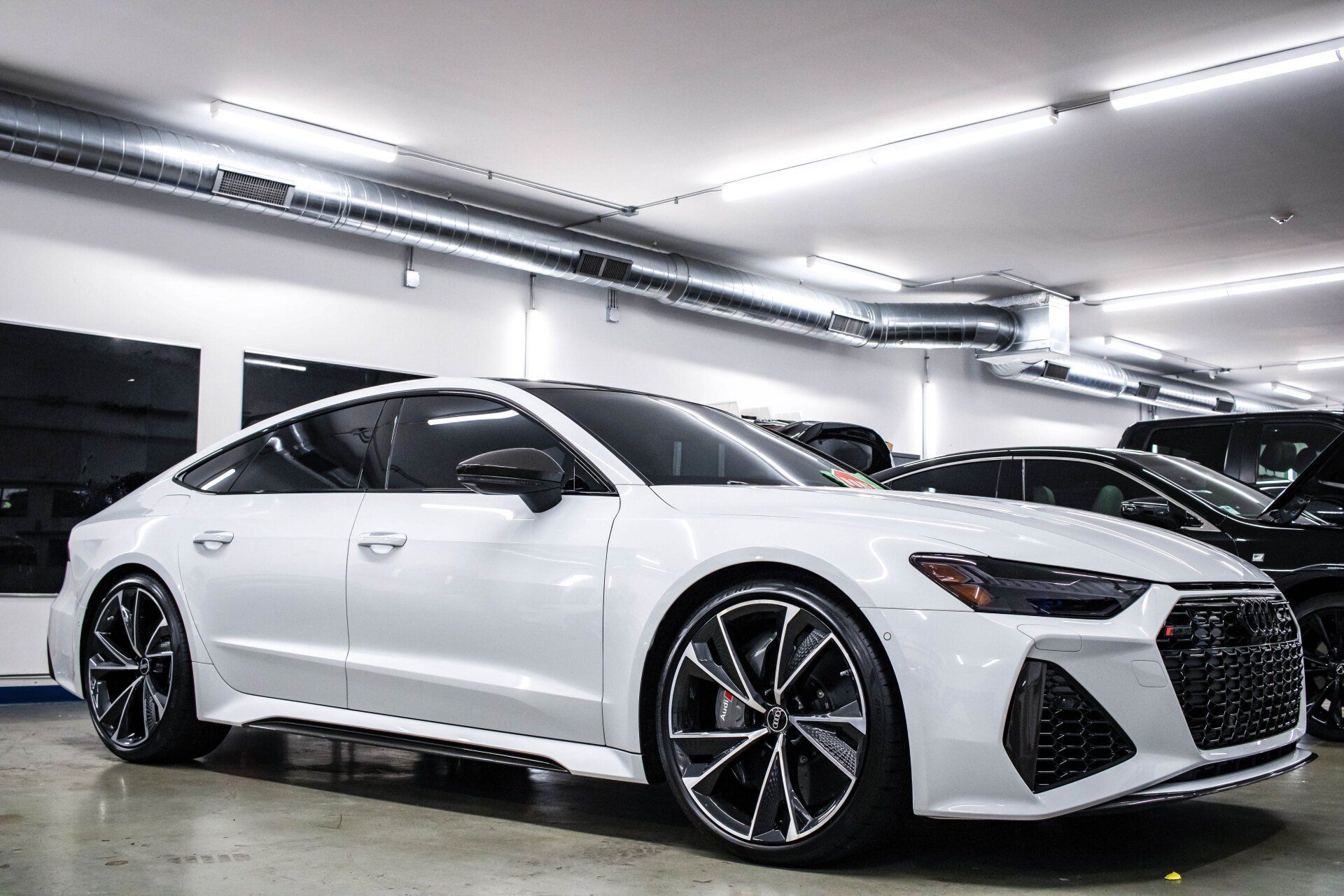 A white audi a7 rs is parked in a showroom.