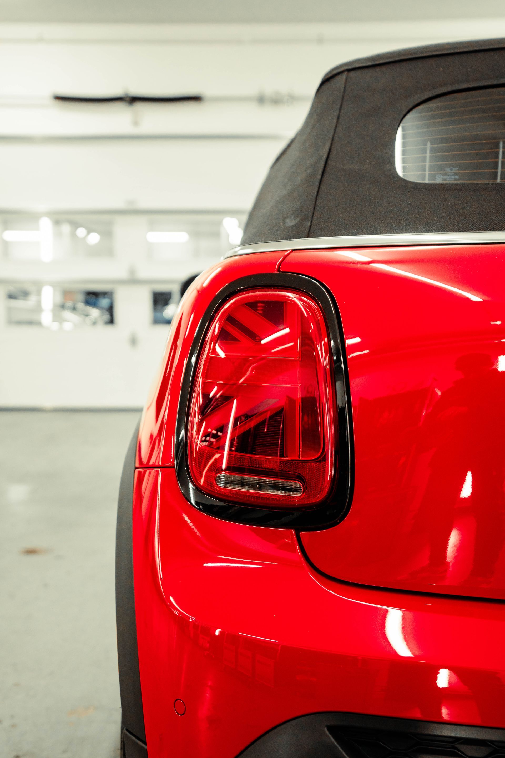 A red car with a black top is parked in a garage.