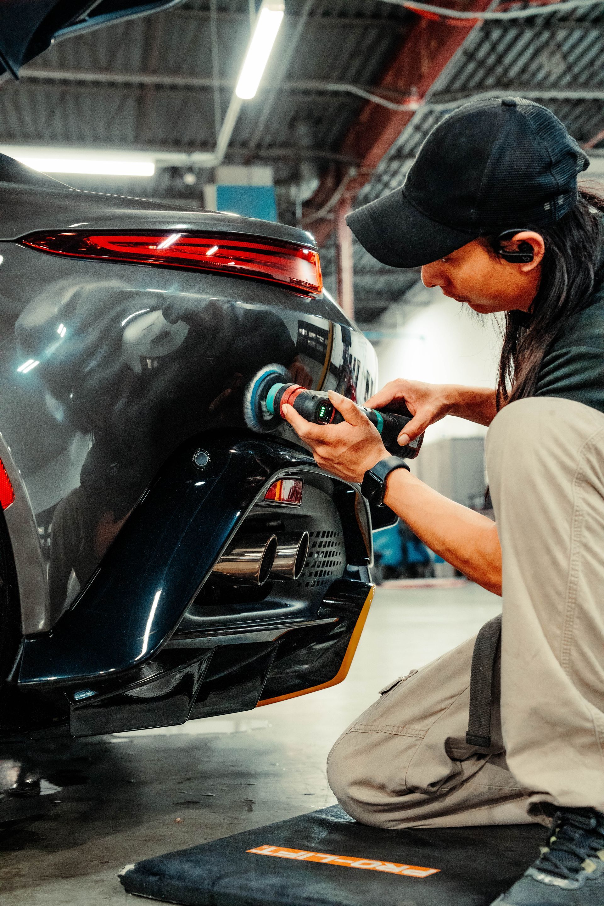 a man is polishing the back of a car in a garage .