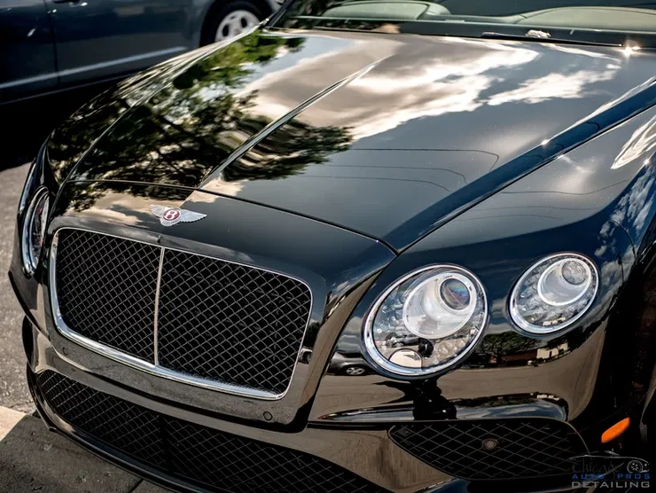 A black bentley is parked on the side of the road.