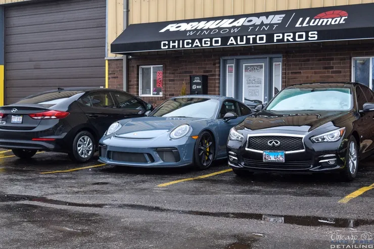 Three cars are parked in front of a chicago auto pros store.