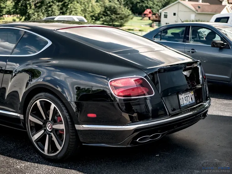 A black bentley continental gt is parked in a parking lot.
