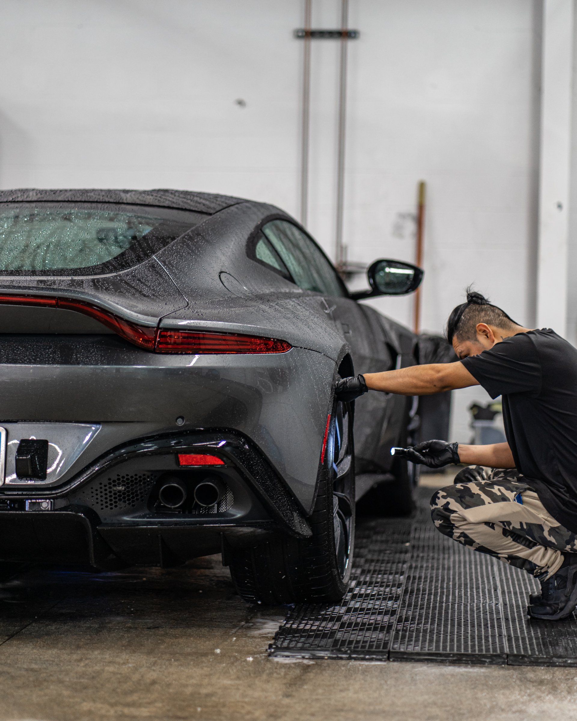 A man is washing a car in a garage.
