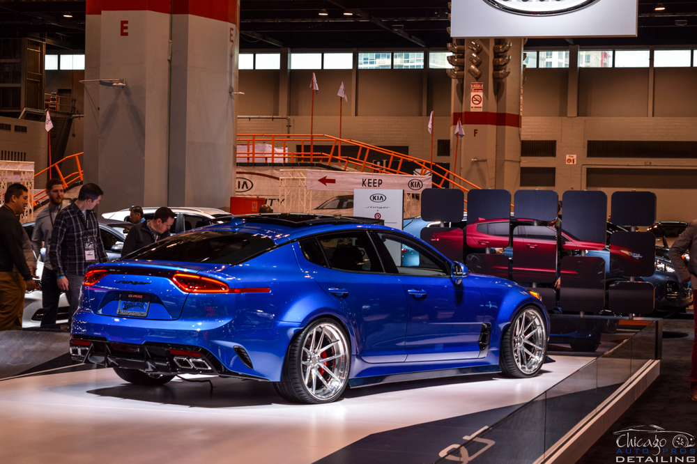 A blue car is on display at a car show.