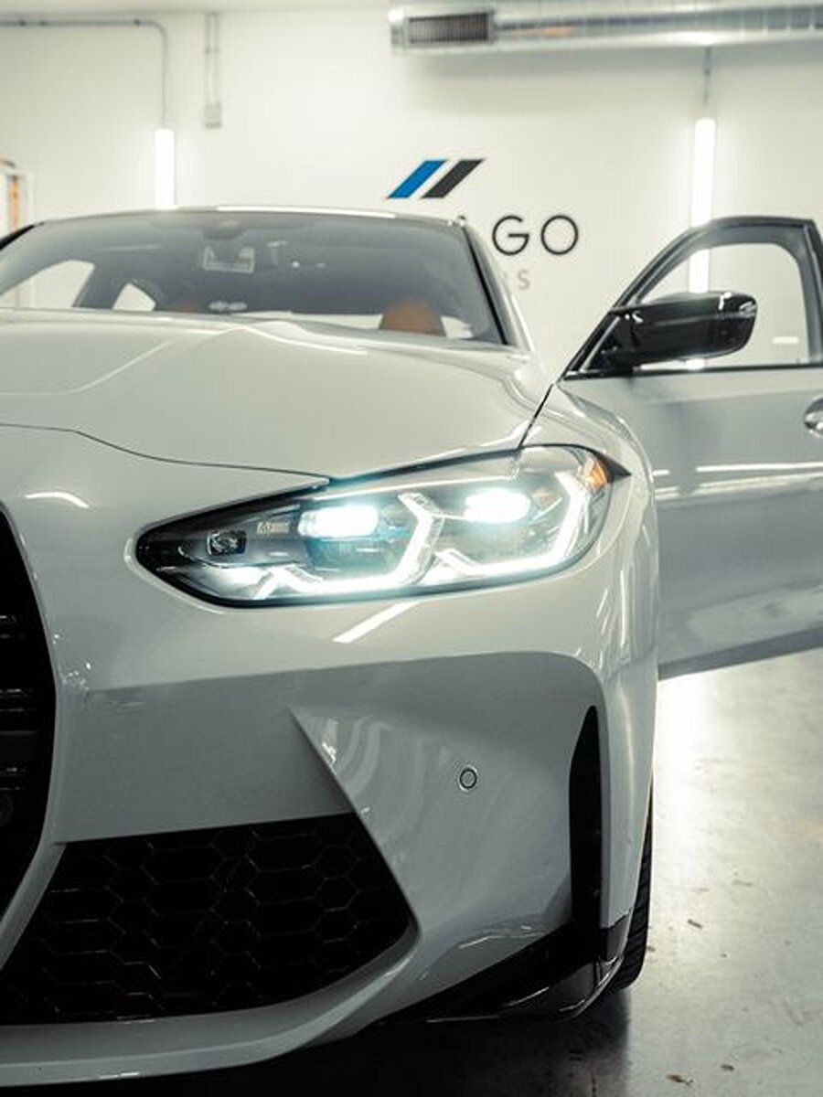 A white car is parked in a garage with the door open.