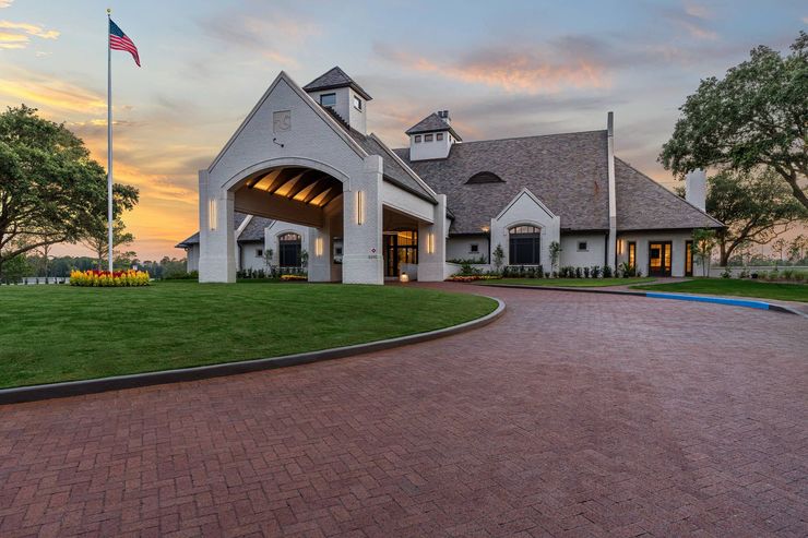 Stone church entrance at sunset with U.S. flag, curved brick drive, and green lawn