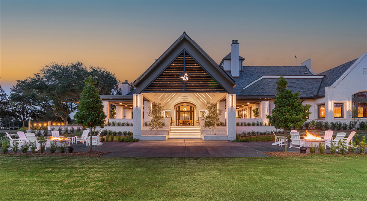 Elegant white event venue at dusk with lit patio seating and a peaked roof, set on a manicured lawn