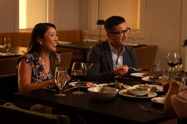 Friends dining at a warmly lit restaurant, smiling over dinner and wine