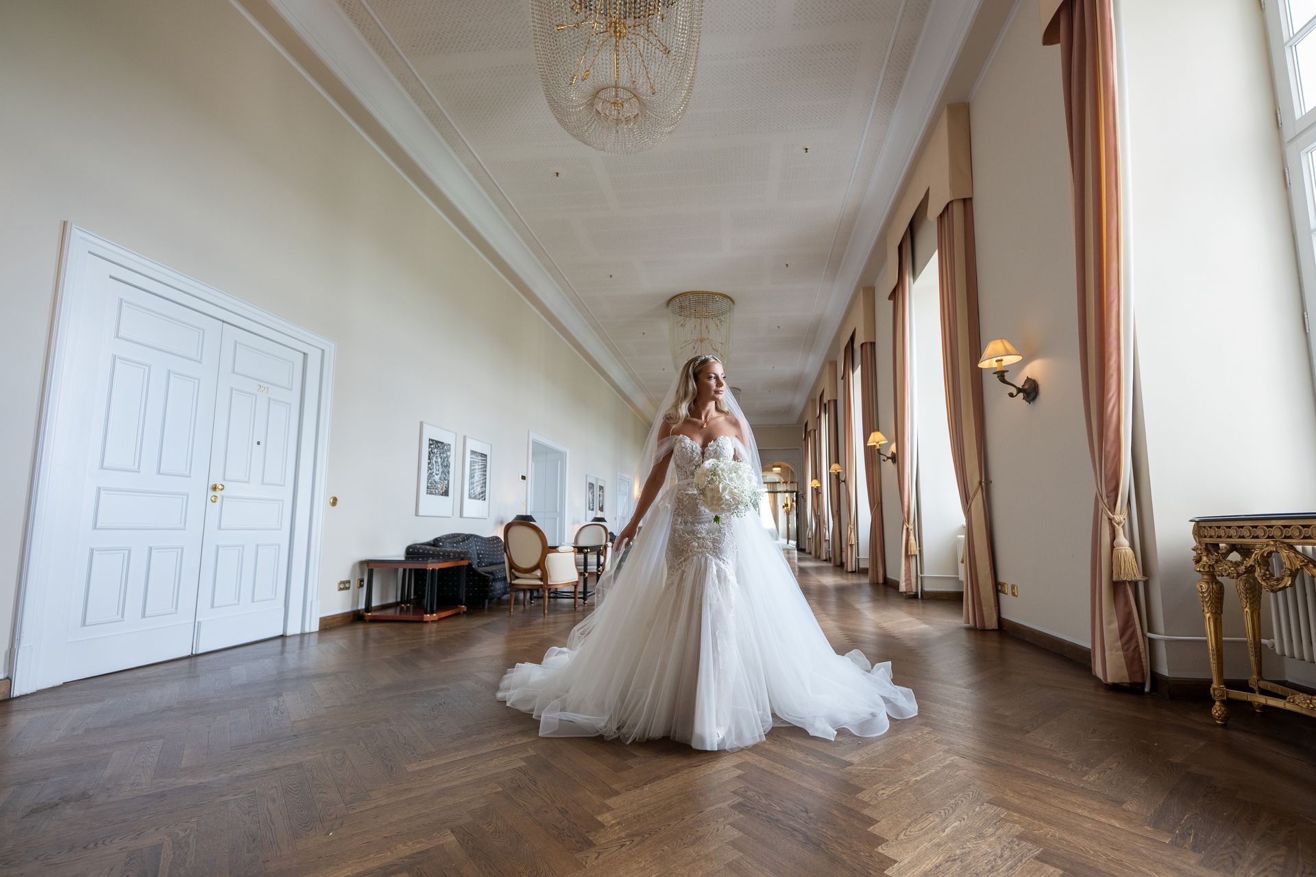 Braut im Spiegelsaal und schaut aus dem Fenster– glamouröse Hochzeitsaufnahme Schloss NRW