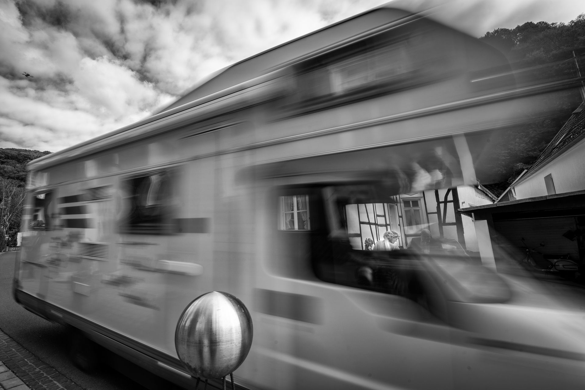 Bewegter Hochzeitsbus mit Fachwerkhäusern, Braut im Fenster zu sehen – kreative Hochzeitsfotografie NRW
