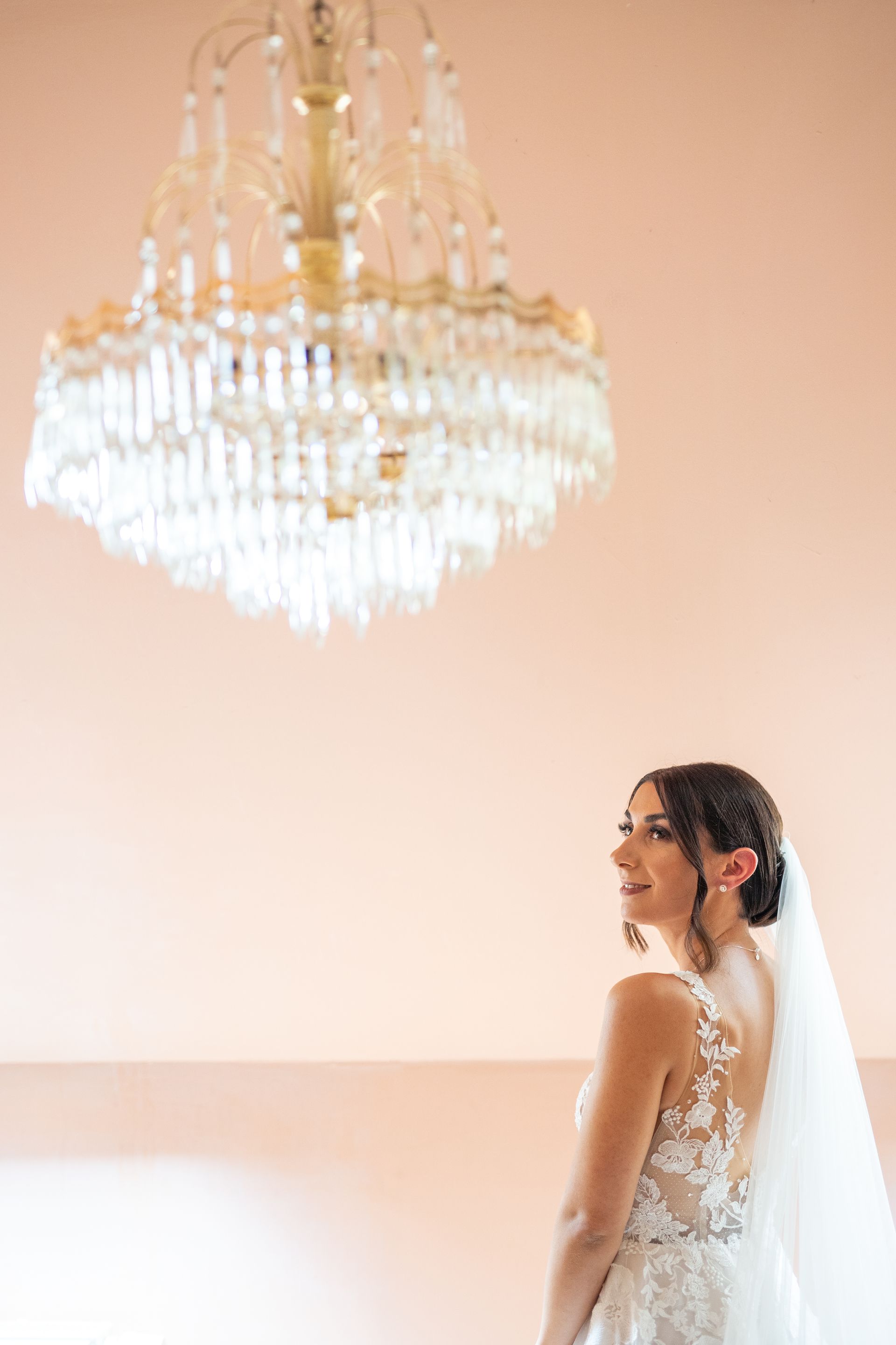 Braut unter Kronleuchter – stilvolle Hochzeitsaufnahme mit edlem Flair
