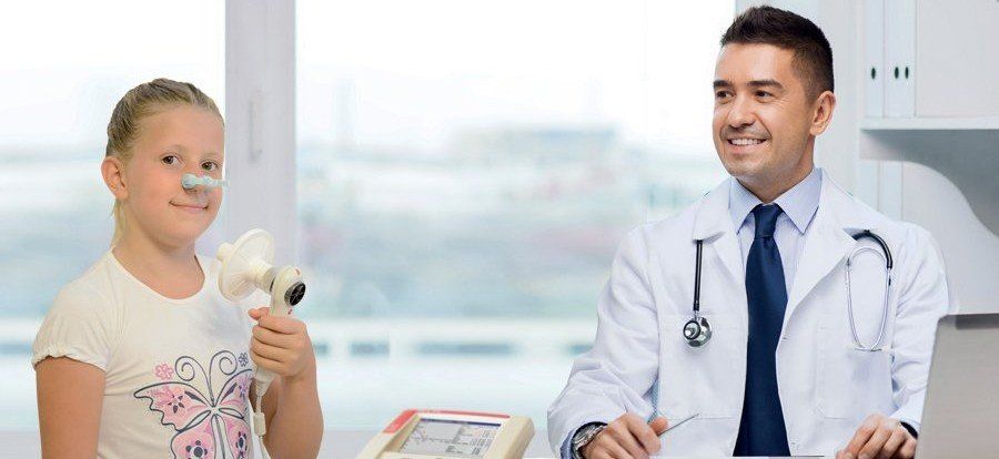 Person in green scrubs holding a black stethoscope against a light background