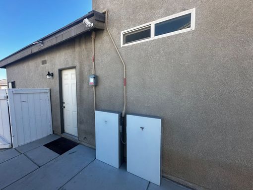 EV charging station plugged into a black car beside a beige wall and stone pillar
