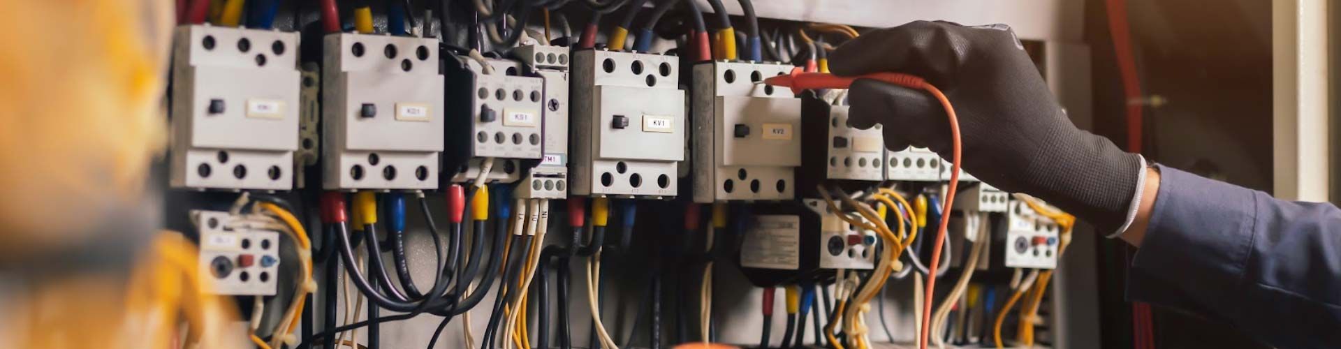 Worker adjusting electrical control panels with wires in an industrial setting