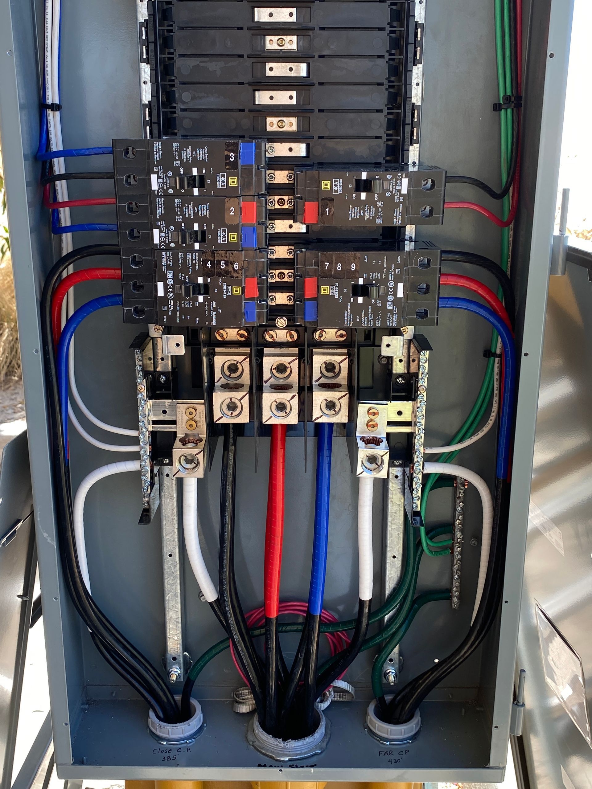 Electrical control panel with circuit breakers, relays, and color-coded wiring inside a metal cabinet