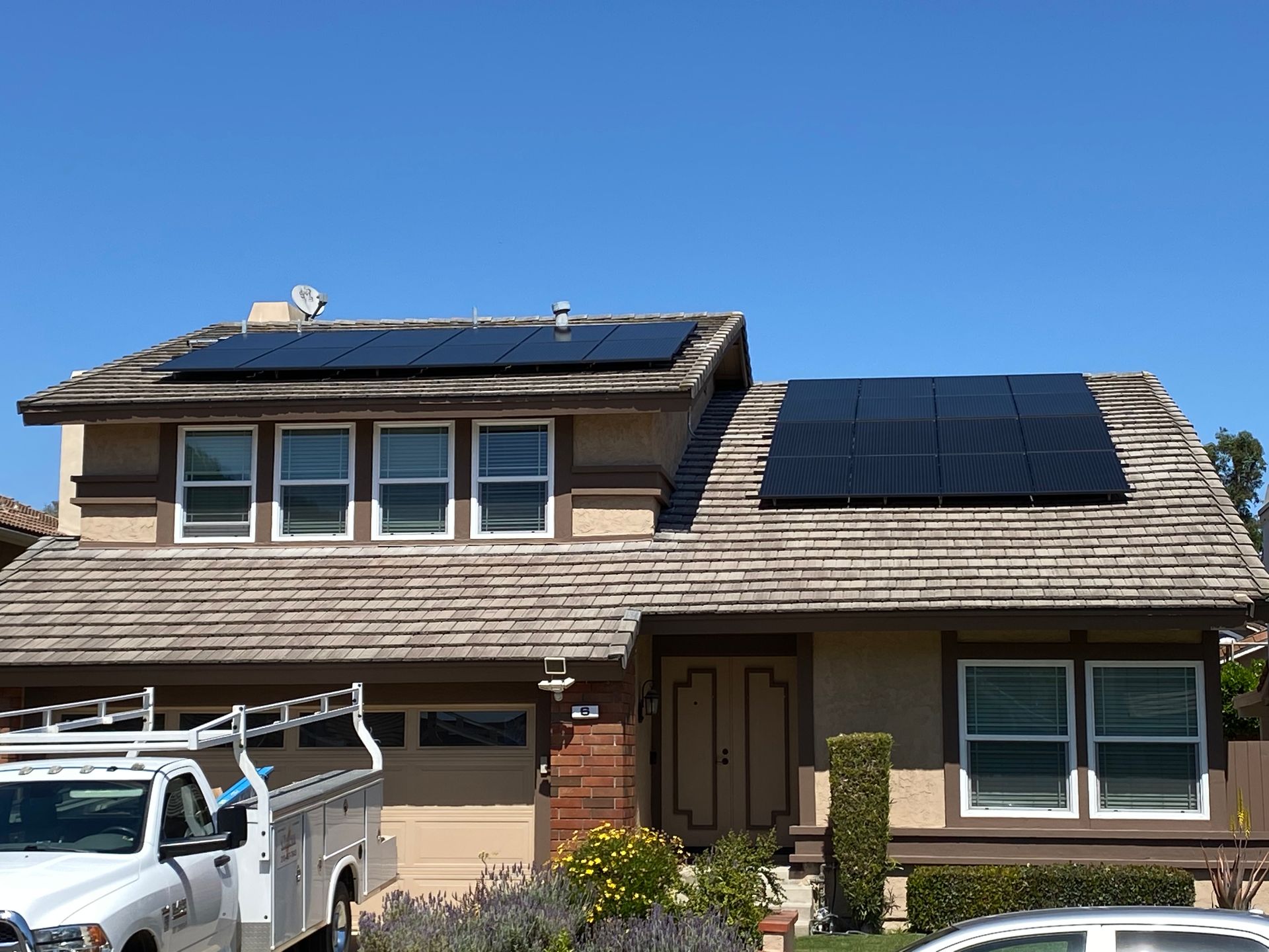 Suburban house with solar panels on the roof and a white utility truck parked in front