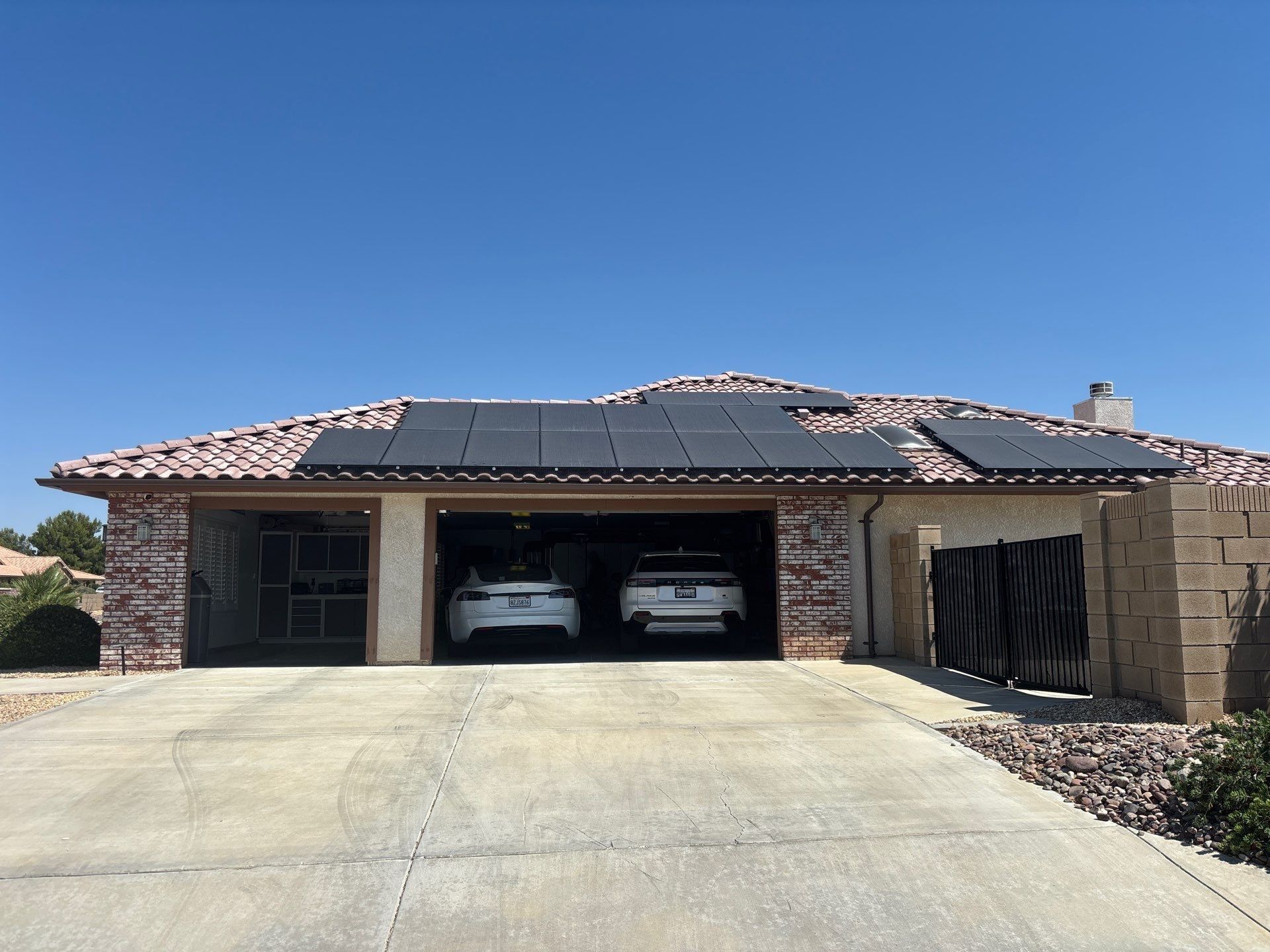 Single-story brick house with two cars parked in the open garage and a wide concrete driveway