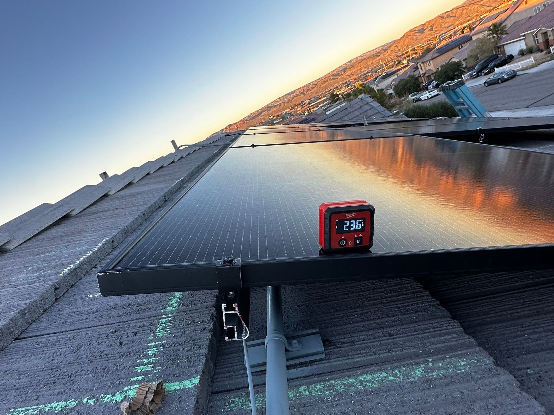 Solar panel overlooking a waterfront at sunset, with a small red digital display in the foreground