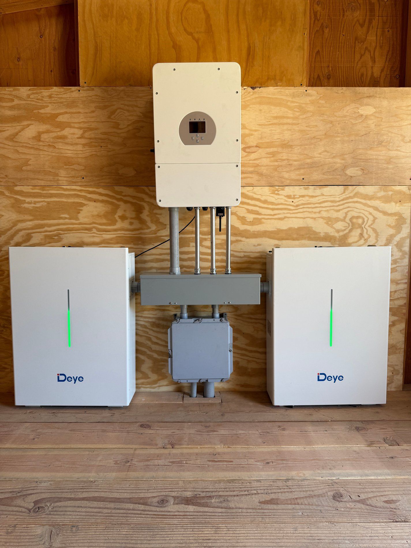 Two white devices with green lights flanking a central mounted control panel on a wooden wall.