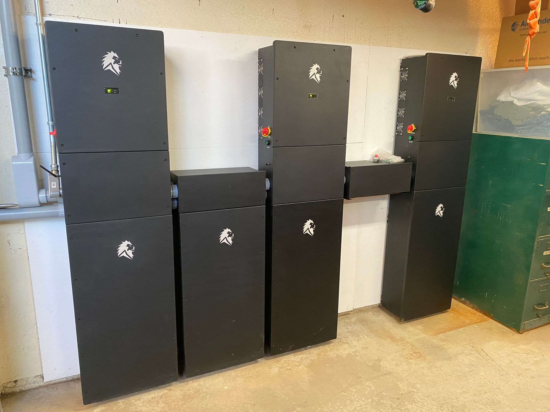 Stacked black storage lockers against a white wall in a room with a green door.