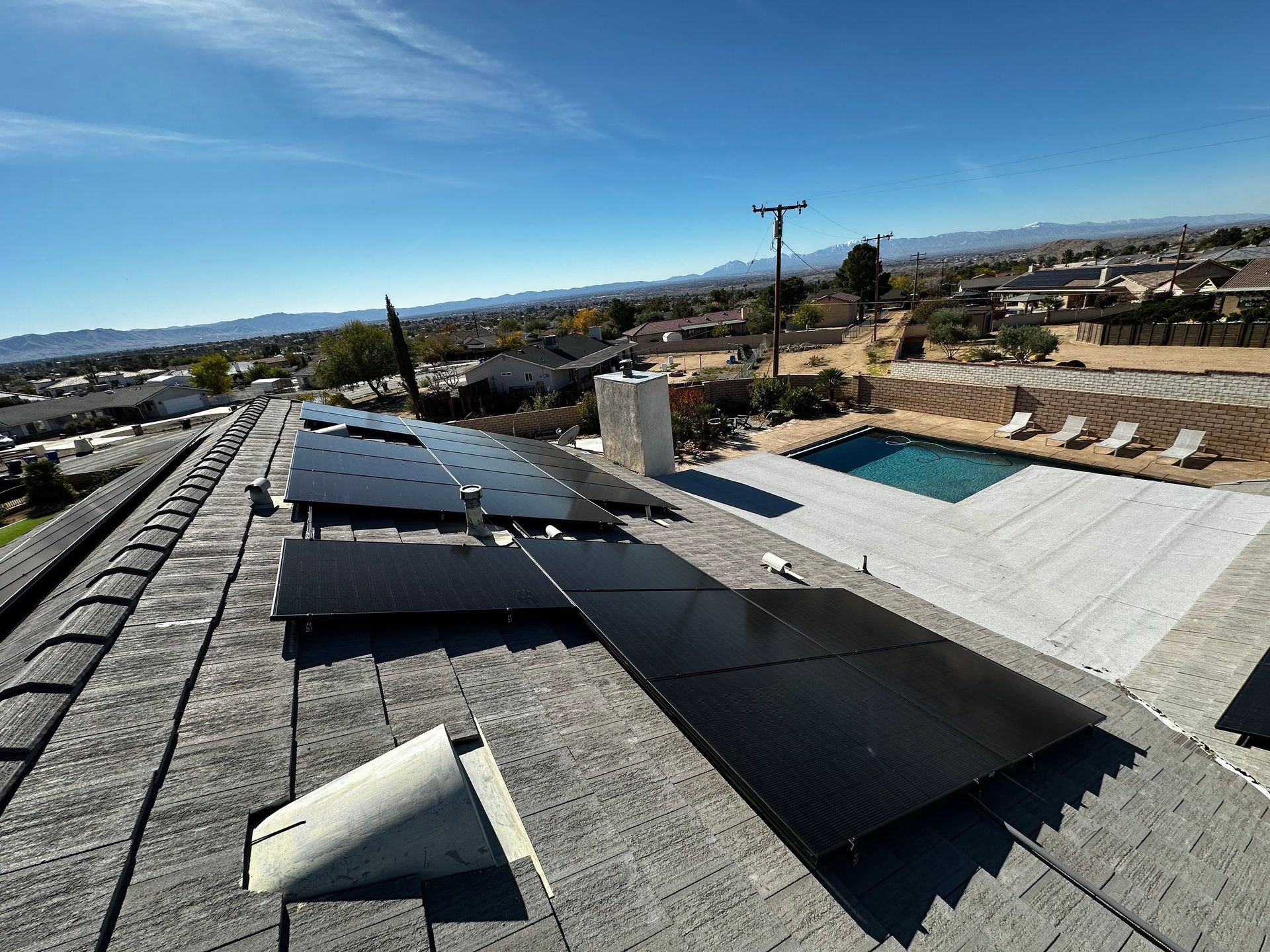Rooftop with solar panels, skylights, and a small pool overlooking a suburban landscape