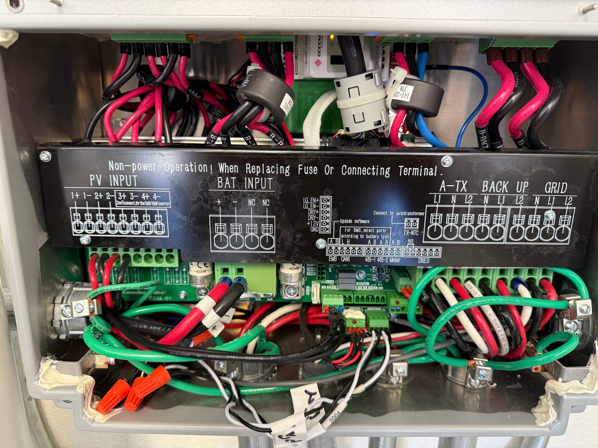Open electrical control panel with tangled red, green, and black wiring and terminal blocks inside a metal box
