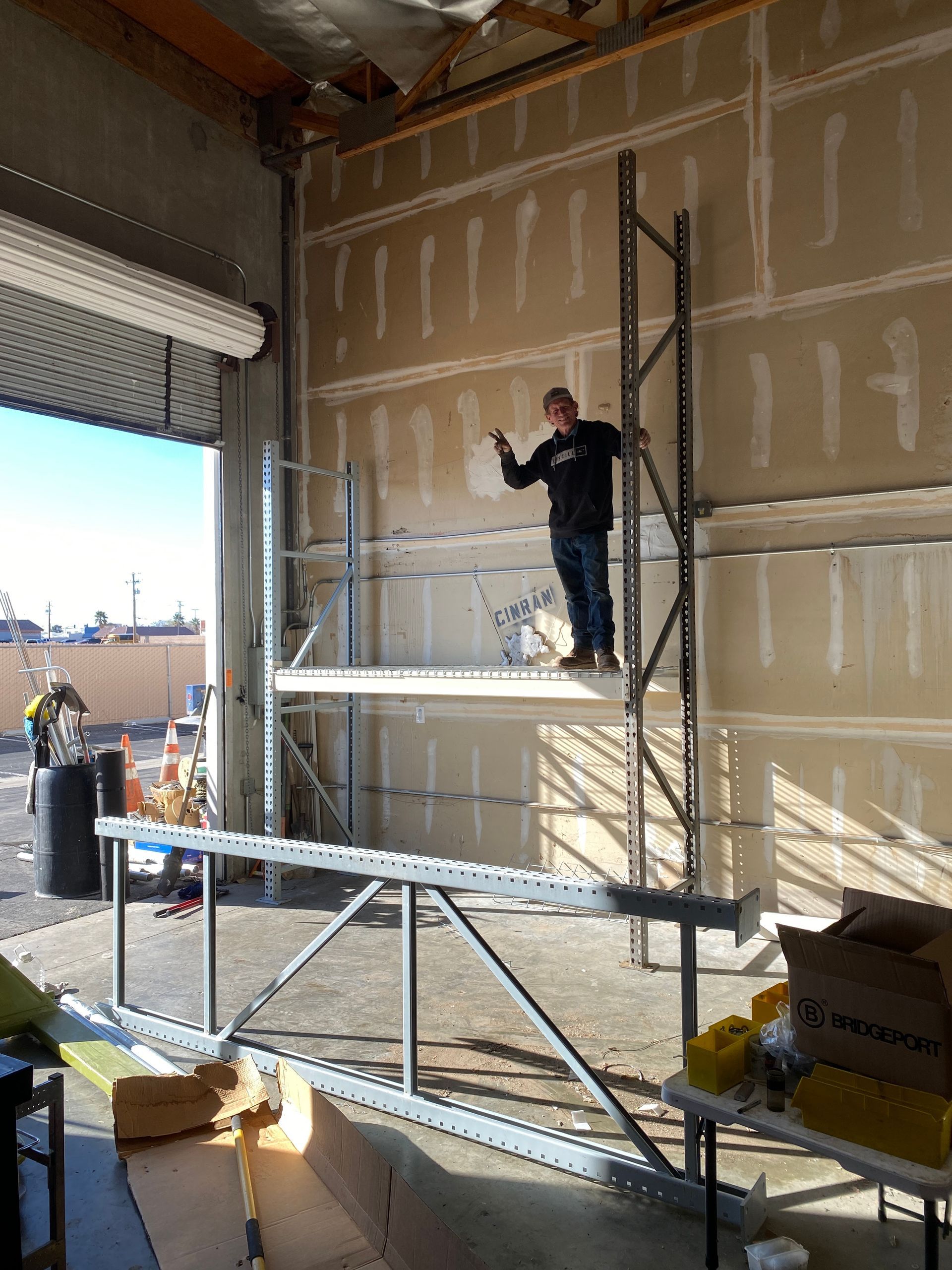 Person standing on a scaffold inside a warehouse under construction.