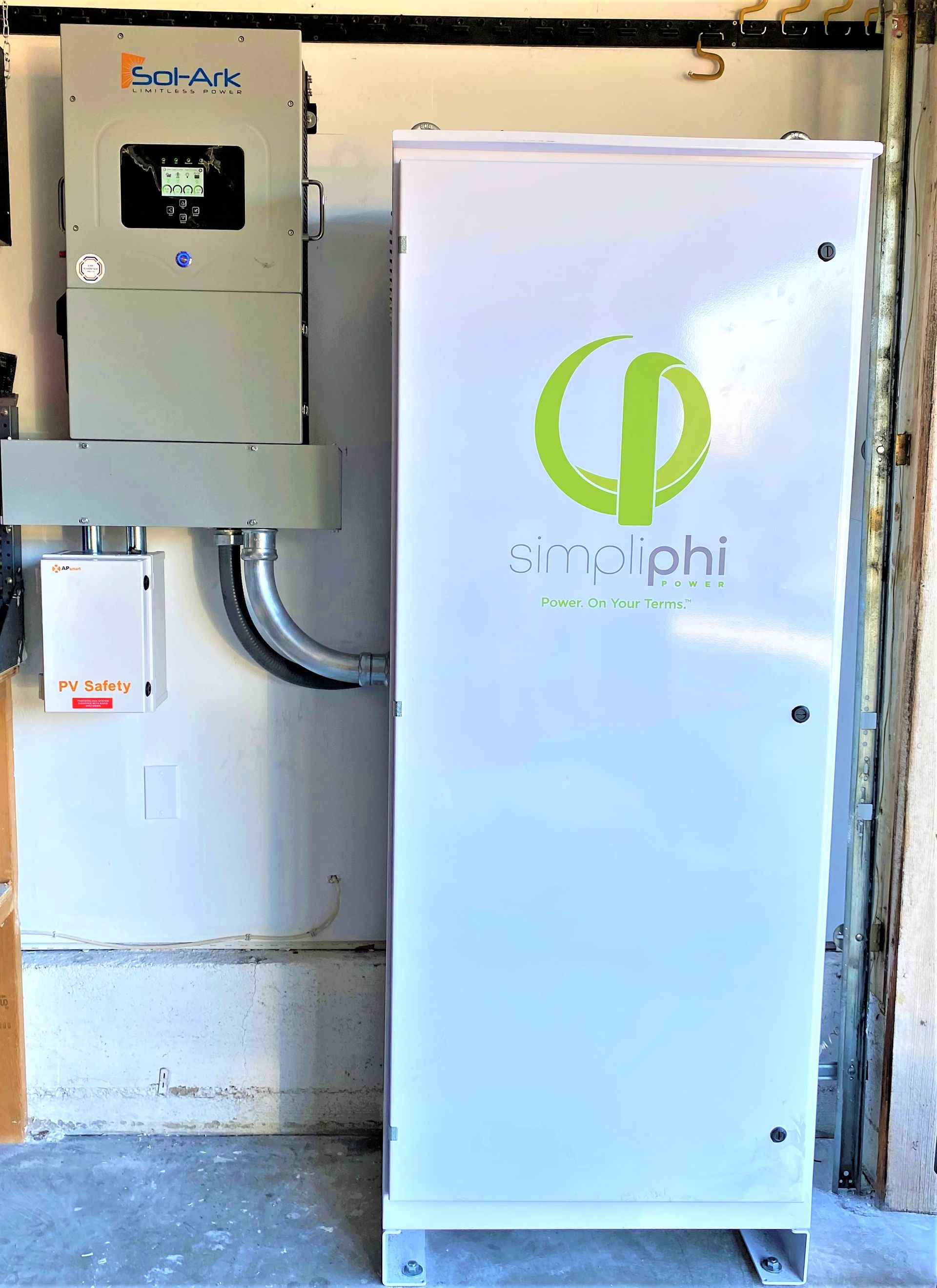 Two wall-mounted electrical cabinets with one bearing a green logo, in a utility room